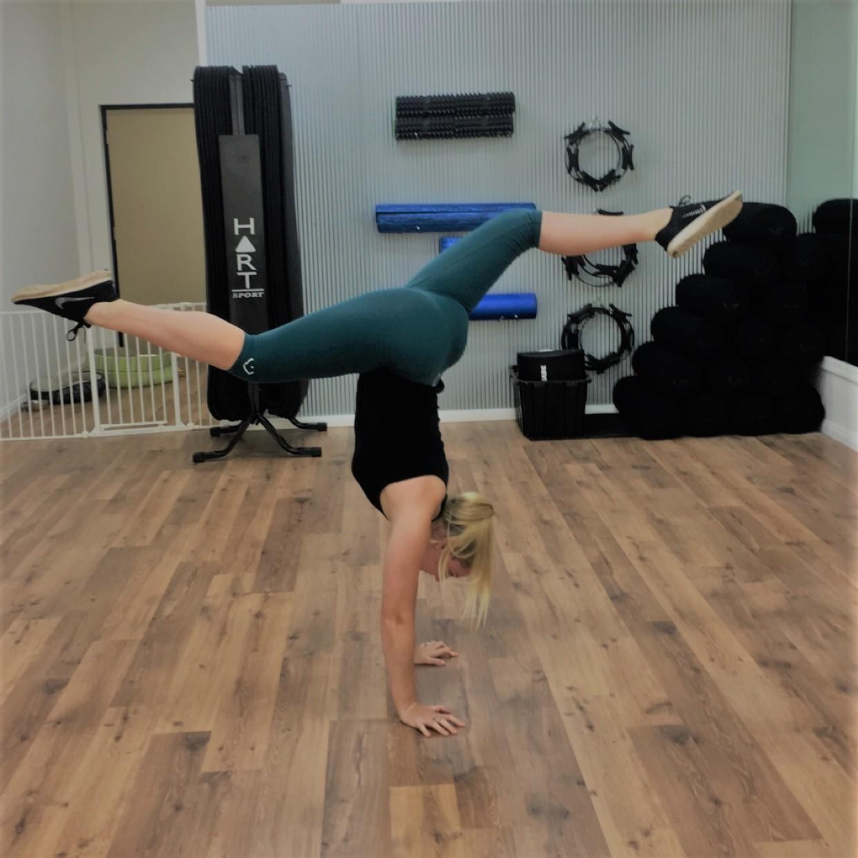 Handstand with split legs showing strength and balance in the Pilates studio